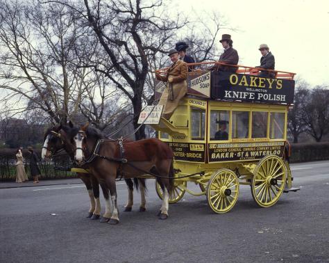 A yellow carriage with three passengers, being hauled by two brown and white horses