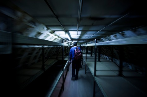A an walks between rows of bunk beds in an underground shelter