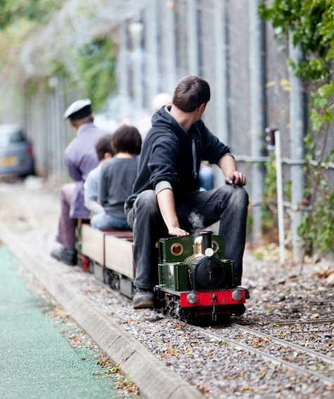 London Transport Museum Miniature Railway. Driver is facing away from camera with three passengers on board behind him